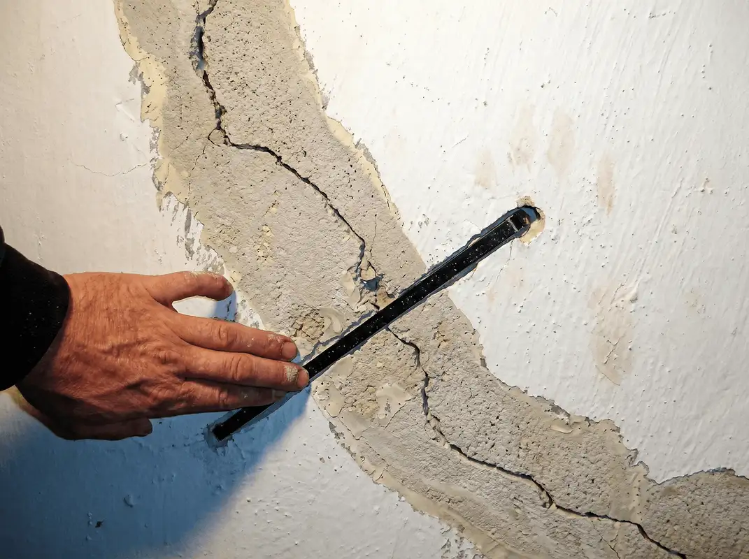A wall with a large crack is being inspected by a professional in Duluth, MN